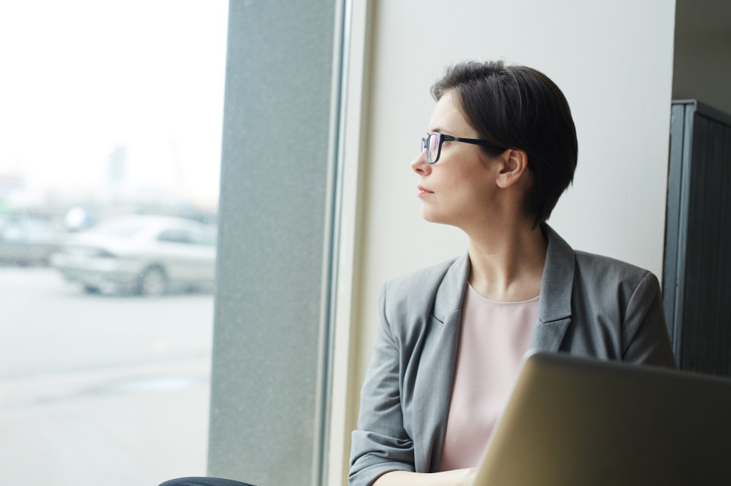 Pensive salesperson looking through office window